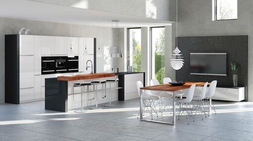 Tischplatten aus warmem Holz lockern die Optik diese schwarz-weißen Küche in hochglänzendem Lack angenehm auf.
